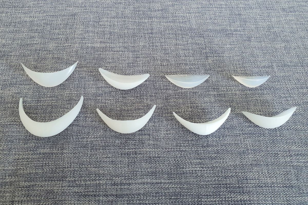 Different shapes and sizes of chin implants displayed on a textured surface to illustrate customization options.