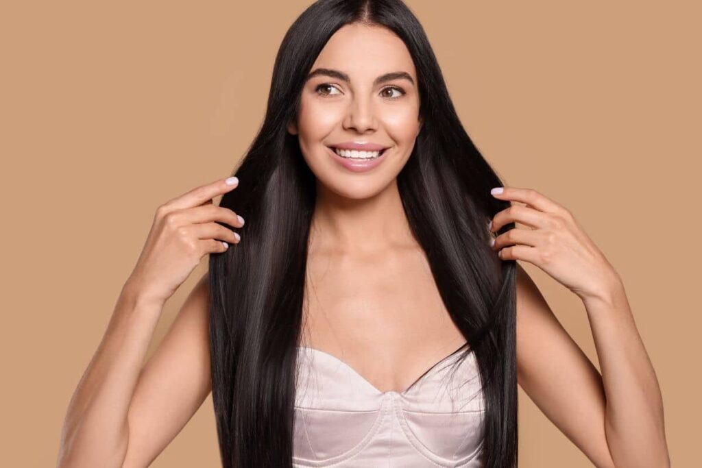 Smiling woman with long, healthy hair showing improved texture and shine from combined Ariessence treatment approach.