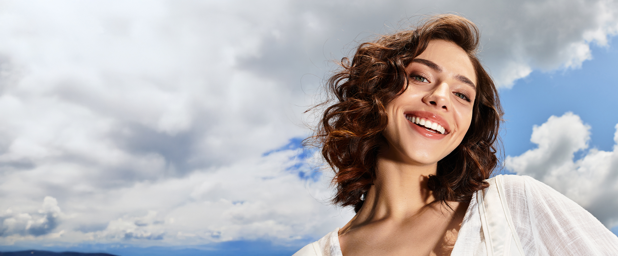 Happy woman outdoors showing glowing skin after Hyperdilute Radiesse, which requires little downtime and easy recovery