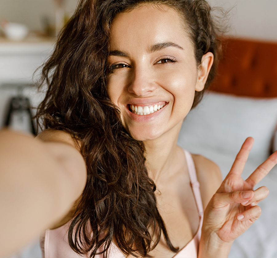Happy woman flashing peace sign, representing ideal candidate for pdgf-bb hair treatment for thinning hair solutions