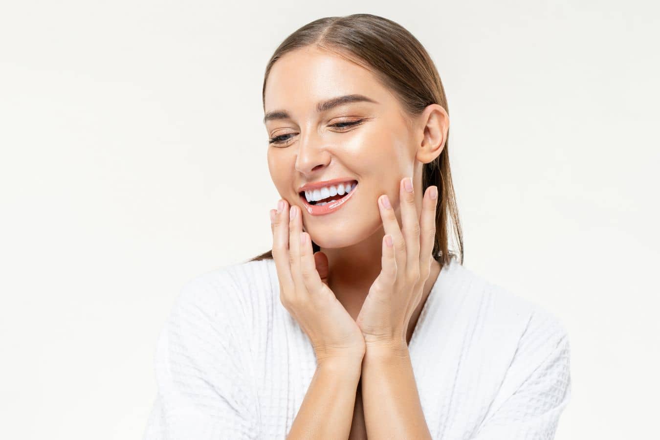 Woman touching smooth glowing skin, representing results of laser resurfacing for acne scars and improved texture